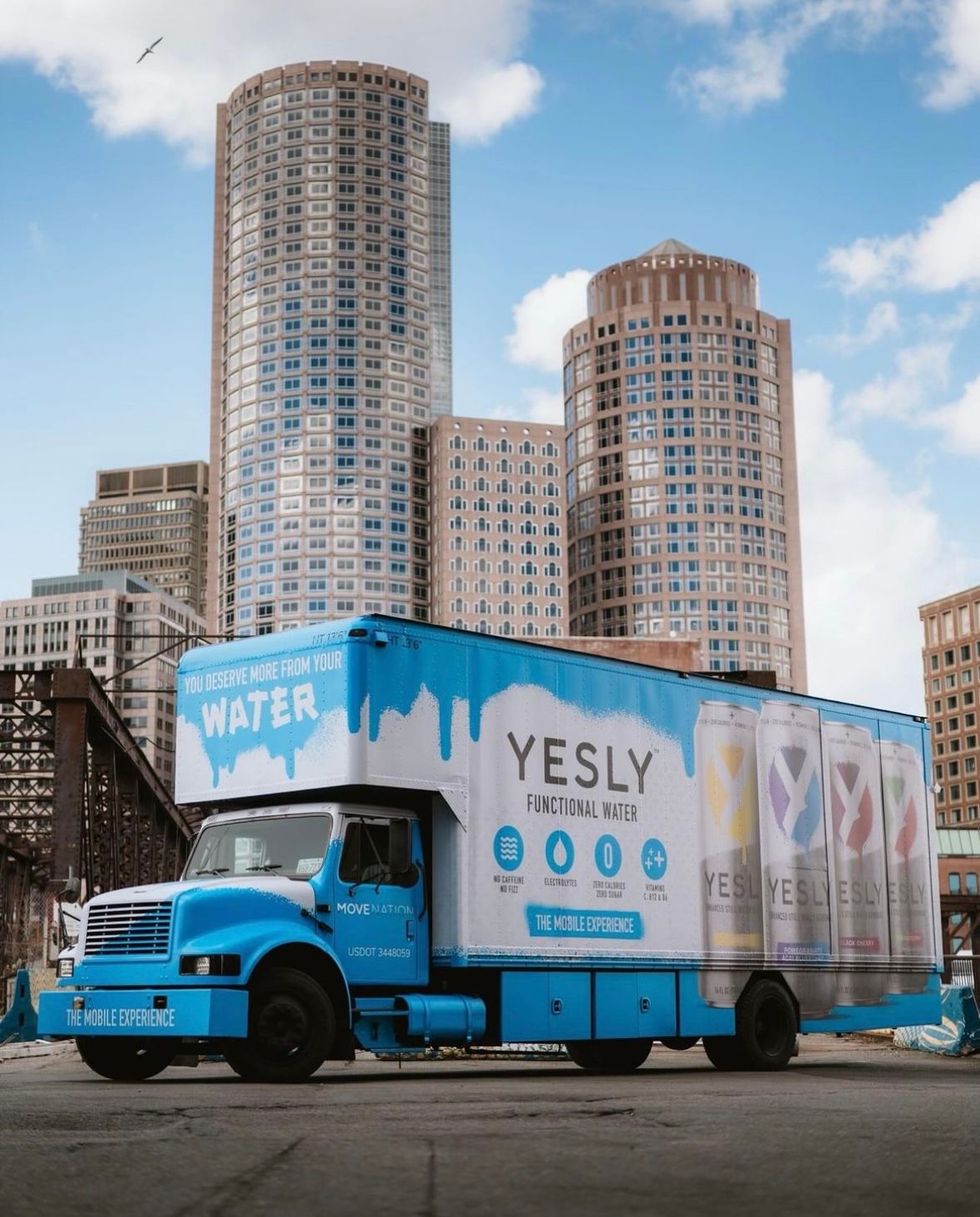 Blue and white box truck with a full printed brand wrap in the city